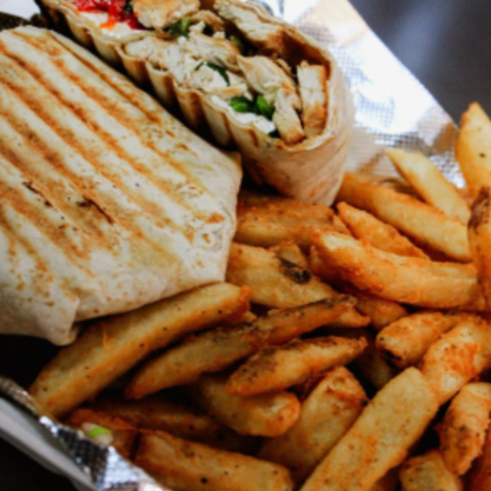 Grilled chicken wrap with fresh greens and a side of crispy potato wedges.