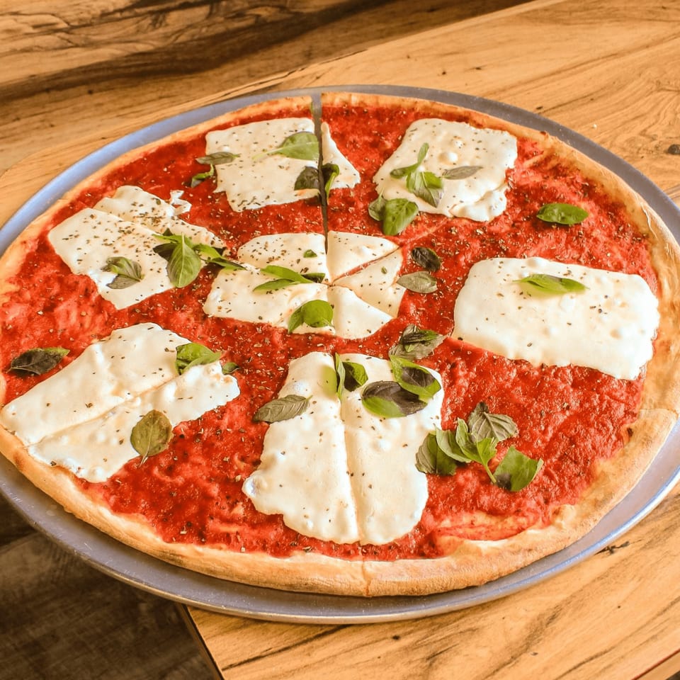 Capri Pizza's Margherita pizza, with fresh mozzarella, tomato sauce, and basil on a wooden table.